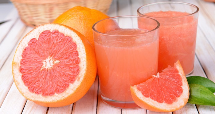 Ripe grapefruit with juice on table close-up